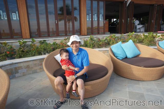 Darwin held by daddy sitting on chair behind Carambola Restaurant in St Kitts .jpg
